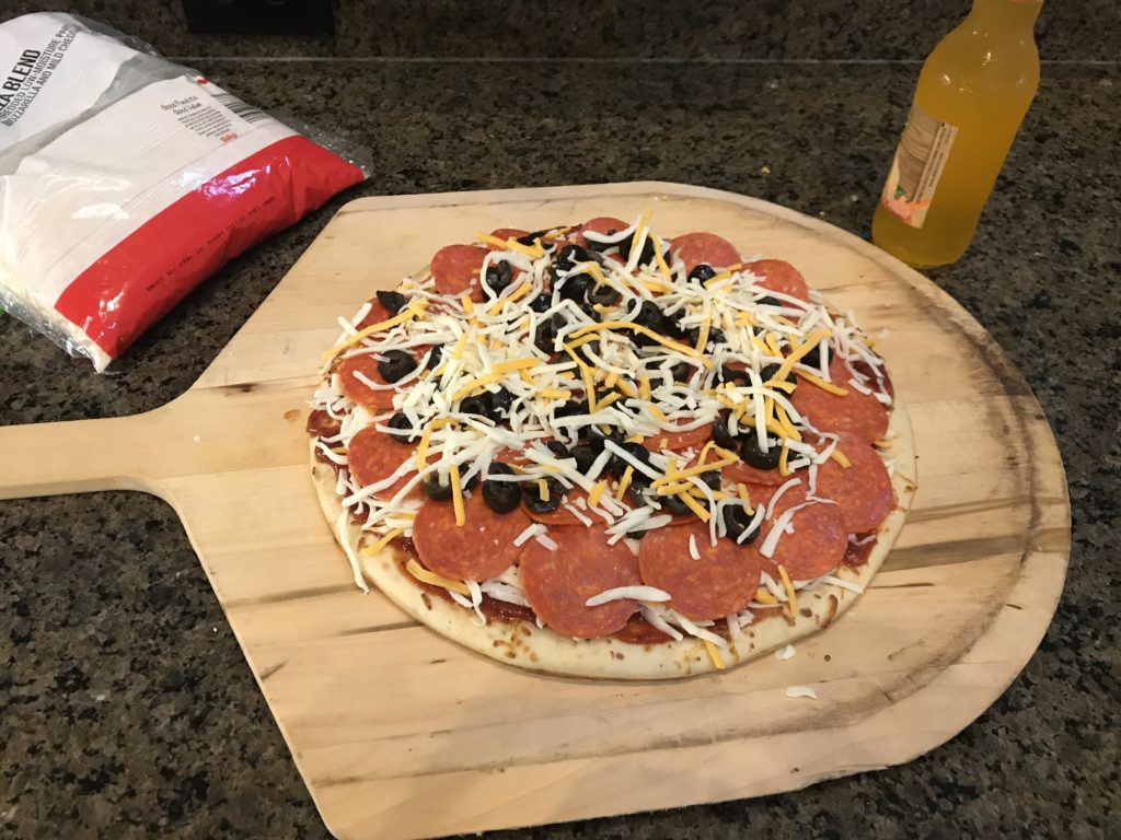 Homemade pizza on a wooden pizza paddle.